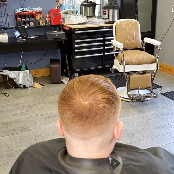 Back-of-chair view of a short red haircut