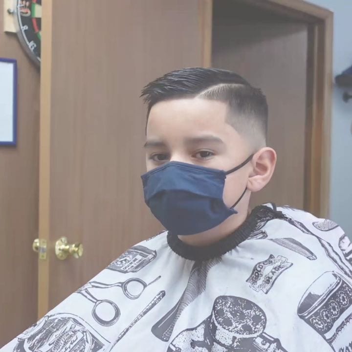 Short haircut beneath a patterned barber cape