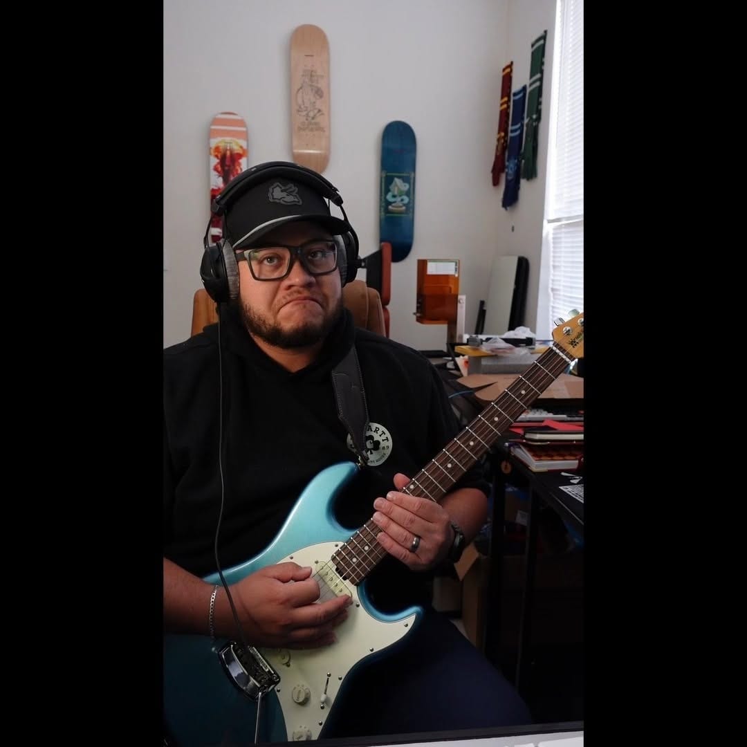A guitarist wearing headphones in a creative room