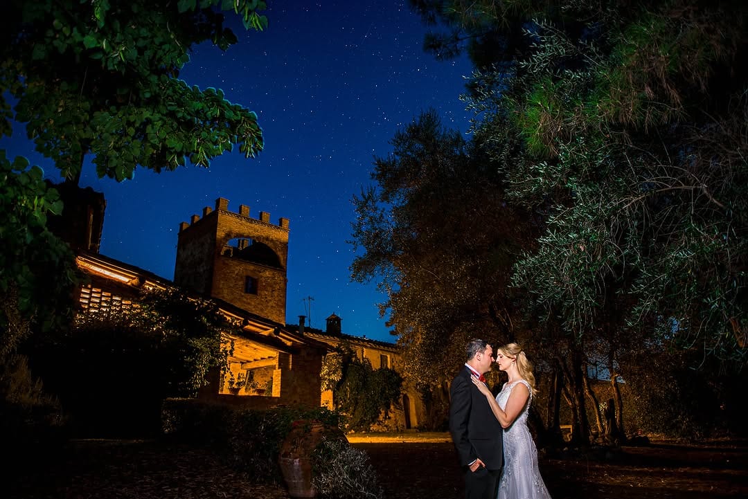 A couple embracing outside a warmly lit stone building at night