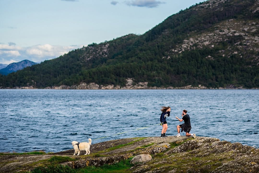 A couple and their dog beside a rocky shoreline