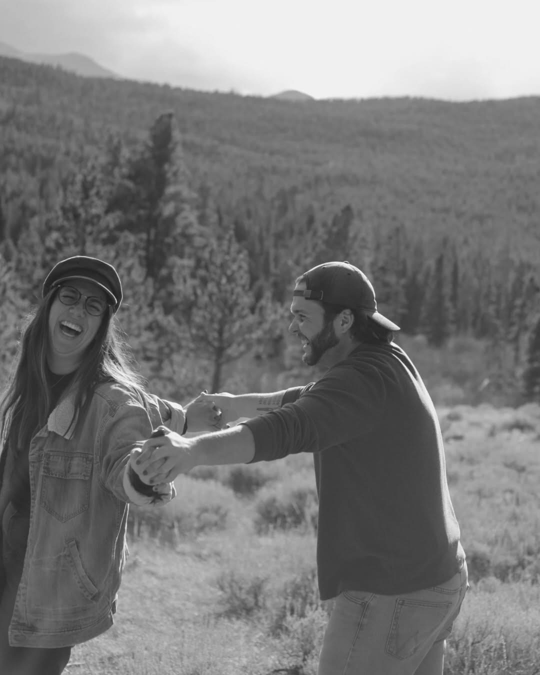 Laughing couple holding hands in a mountain landscape