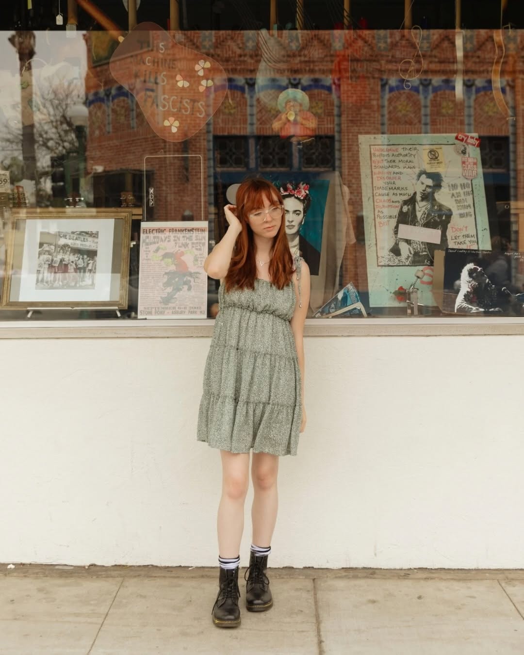 Senior portrait of a young woman in a dress and boots outside a storefront