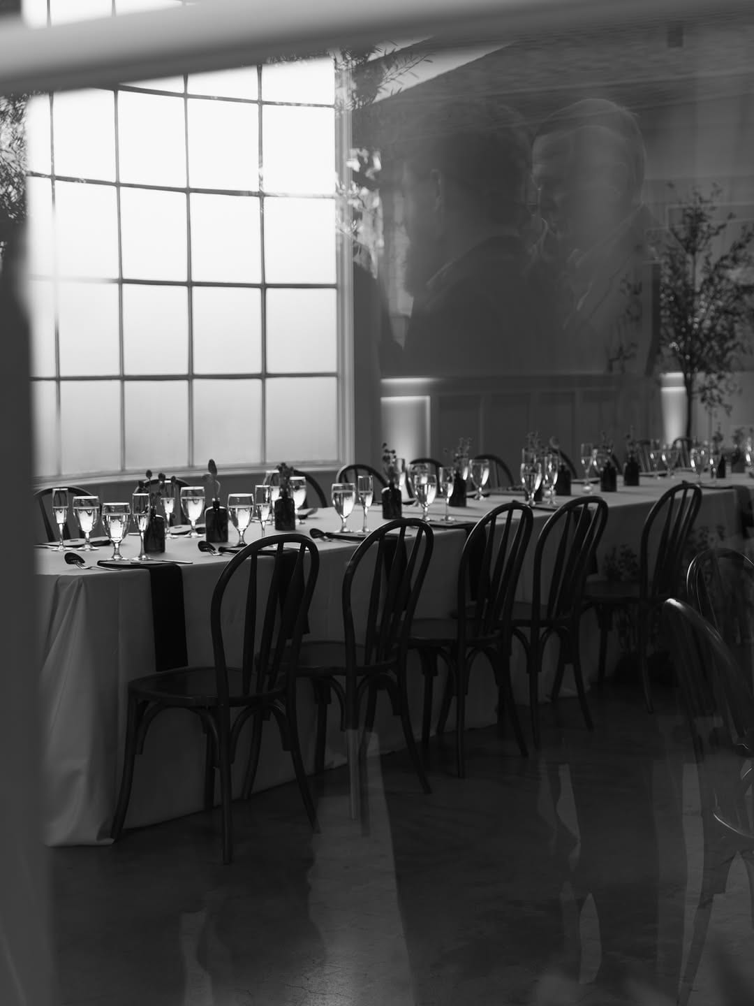Black and white decorated wedding reception room with long tables and windows